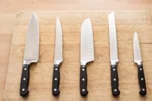 Cinq types de couteaux de cuisine différents alignés sur un plan de travail
